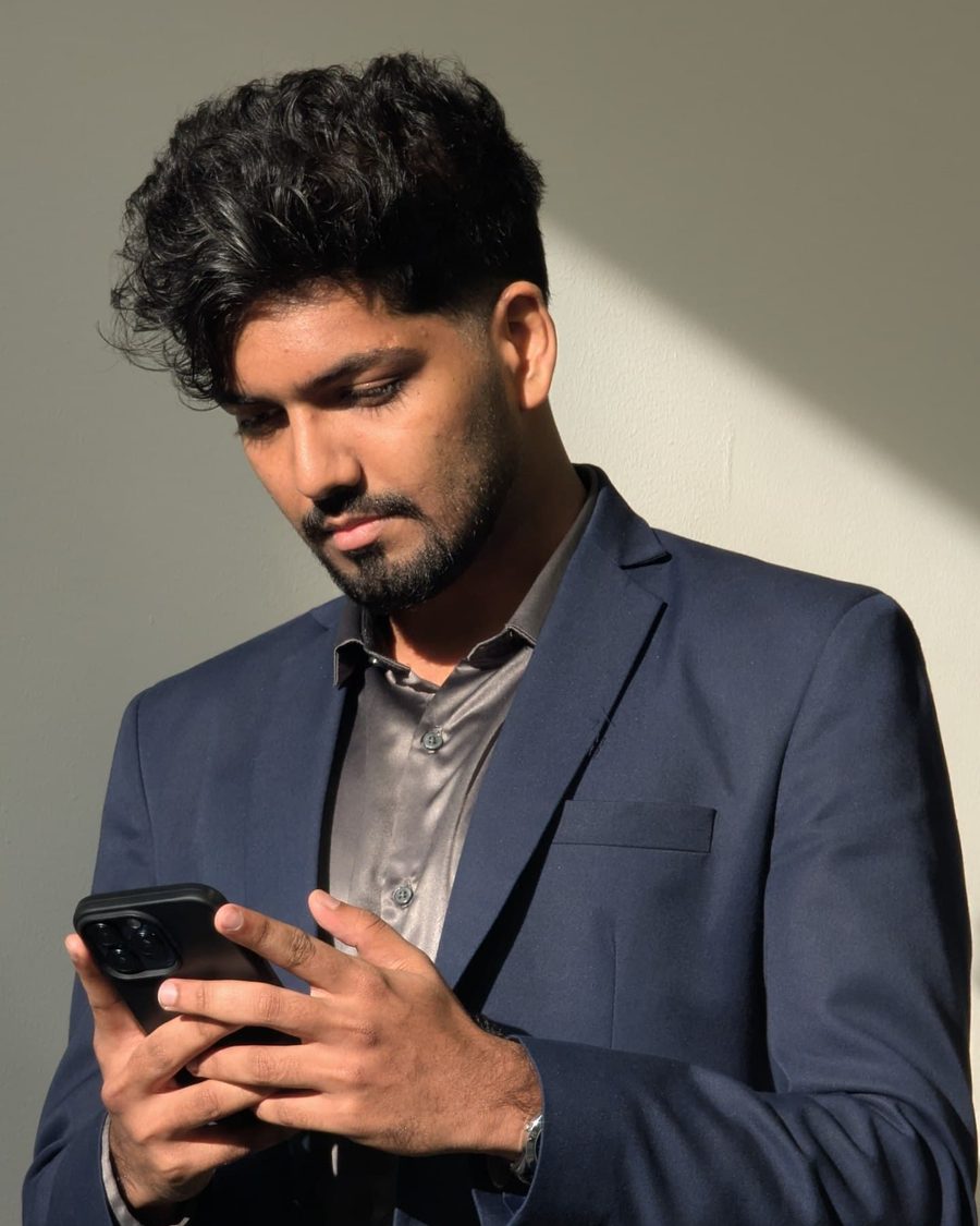 Nikhil Mukundan in a navy suit, checking his phone